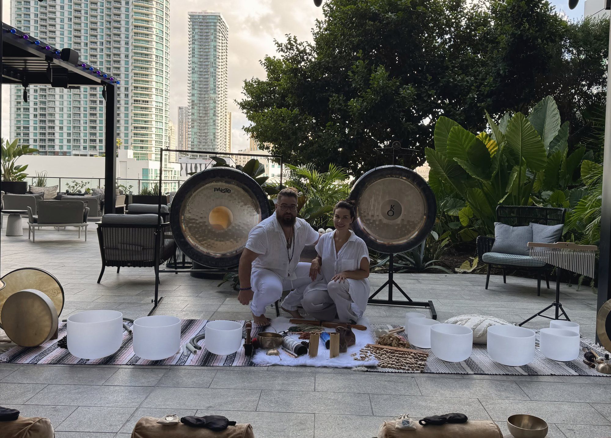 Karina and Juan seated between two gongs on the Puttshack terrace, crystal bowls in front of them